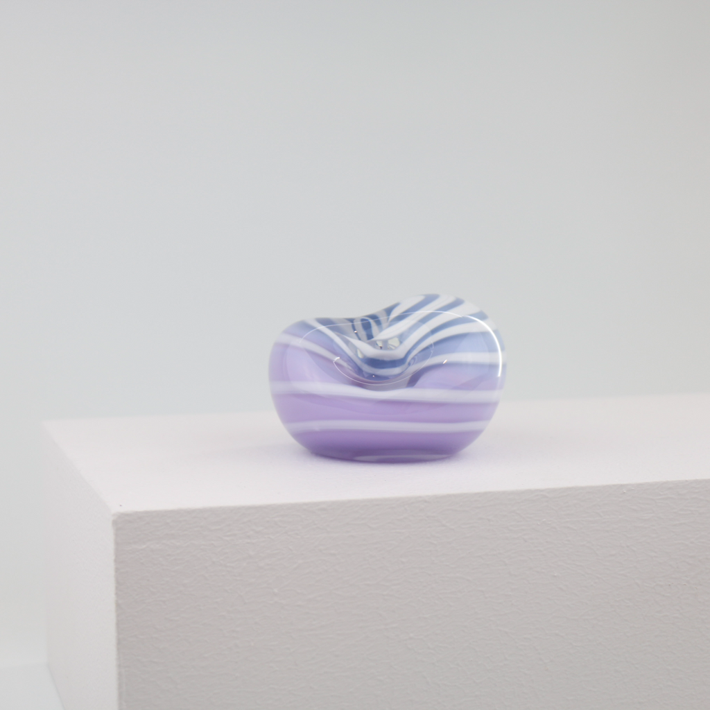 A little glass keepsake that will brighten up any desk, coffee table, or bookshelf. It is purple with a white swirl.
